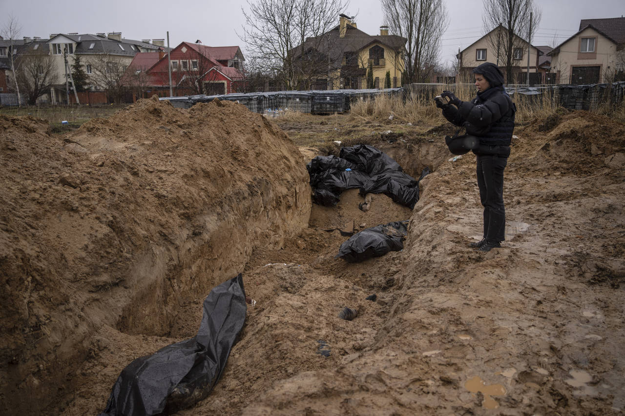 FILE - A journalist takes video of a mass grave in Bucha, on the outskirts of Kyiv, Ukraine, Sunday...