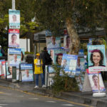 
              A volunteer stands amongst billboards for candidates outside a polling station in Sydney, Australia, Monday, May 9, 2022. Early voting has begun in Australia's federal election with the opposition party hoping the first ballots will reflect its lead over the government in an opinion poll. (AP Photo/Mark Baker)
            