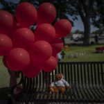 
              A teddy bear sits alone on a park bench under a bouquet of red balloons at the memorial site for victims of the mass shooting at Robb Elementary School in the town square of Uvalde, Texas on Saturday, May 28, 2022. In a town as small as Uvalde, even those who didn't lose their own child lost someone. Some say now that closeness is both their blessing and their curse: they can lean on each other to grieve. But every single one of them is grieving. (AP Photo/Wong Maye-E)
            