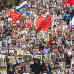 
              People carry portraits of relatives who fought in World War II, and Russian and Soviet flags, during the Immortal Regiment march in Ulan-Ude, the regional capital of Buryatia, a region near the Russia-Mongolia border, Russia, Monday, May 9, 2022, marking the 77th anniversary of the end of World War II. (AP Photo)
            