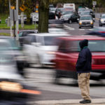 
              A pedestrian waits to cross Roosevelt Boulevard, in Philadelphia, Tuesday, April 19, 2022. Roosevelt Boulevard is an almost 14-mile maze of chaotic traffic patterns that passes through some of the city's most diverse neighborhoods and Census tracts with the highest poverty rates. Driving can be dangerous with cars traversing between inner and outer lanes, but biking or walking on the boulevard can be even worse with some pedestrian crossings longer than a football field and taking four light cycles to cross. (AP Photo/Matt Rourke)
            