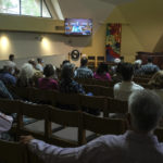 
              Senior pastor Saran Halverson-Cano, who has tested positive for coronavirus, is seen delivering a sermon on a TV screen at Irvine United Congregational Church in Irvine, Calif., Sunday, May 8, 2022. (AP Photo/Ringo H.W. Chiu)
            
