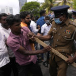 
              A Sri Lankan police officer tries to snatch a baton from a government supporter during clashes outside prime minister's residence in Colombo, Sri Lanka, Monday, May 9, 2022. Authorities deployed armed troops in the capital Colombo on Monday hours after government supporters attacked protesters who have been camped outside the offices of the country's president and prime minster, as trade unions began a “Week of Protests” demanding the government change and its president to step down over the country’s worst economic crisis in memory. (AP Photo/Eranga Jayawardena)
            