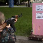 
              Victoria, 7, uses a plastic Kalashnikov rifle to shoot balls at a portrait of Russian President Vladimir Putin, at a street attraction in the centre of Lviv, Ukraine on Saturday, May 14, 2022. The banner reads in Ukrainian: It's not a shame to miss. It's a shame not to try to shoot! Glory to Ukraine, Death to our enemies!. (AP Photo/Emilio Morenatti)
            