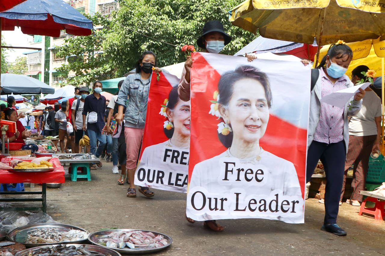 FILE - Protesters walk through a market with posters of ousted Myanmar leader Aung San Suu Kyi at K...