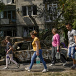 
              Residents carry water in front of an apartment building damaged in an overnight missile strike, in Sloviansk, Ukraine, Tuesday, May 31, 2022. (AP Photo/Francisco Seco)
            