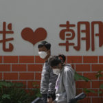 
              A couple wearing face masks walk by a wall displaying a words "I Love Chaoyang" as they heading to get tested for COVID-19 in the Chaoyang district on Wednesday, May 11, 2022, in Beijing. Shanghai reaffirmed China's strict "zero-COVID" approach to pandemic control Wednesday, a day after the head of the World Health Organization said that was not sustainable and urged China to change strategies. (AP Photo/Andy Wong)
            