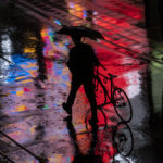 
              A man walks his bicycle in the rain Monday, May 9, 2022, in Tokyo. (AP Photo/Kiichiro Sato)
            