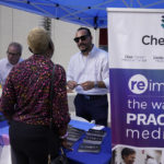 
              Diego Osorio, center, with ChenMed, talks to a job seeker at the Venture Miami Tech Hiring Fair Thursday, April 14, 2022, in Miami.  America’s employers added 428,000 jobs in April, extending a streak of solid hiring that has defied punishing inflation, chronic supply shortages, the Russian war against Ukraine and much higher borrowing costs.  (AP Photo/Marta Lavandier)
            