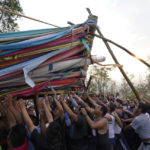 
              People work to lower a heavy, wooden cross from a hilltop as part of celebrations marking the day of the Holy Cross, in the Santa Cruz Xochitpec neighborhood of Mexico City, late Monday, May 2, 2022. The importance of the fabric-draped cross is reflected in the town's very name, which means "Holy Cross of the Flowered Hill." (AP Photo/Eduardo Verdugo)
            