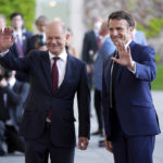 
              German Chancellor Olaf Scholz, left, and French president Emmanuel Macron wave to journalists prior to a meeting at the chancellery in Berlin, Germany, Monday, May 9, 2022. (AP Photo/Michael Sohn)
            