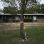 
              A school building stands behind a tree with an American flag and crime scene tape at Robb Elementary School in Uvalde, Texas Monday, May 30, 2022. On May 24, 2022, an 18-year-old entered the school and fatally shot several children and teachers. (AP Photo/Jae C. Hong)
            