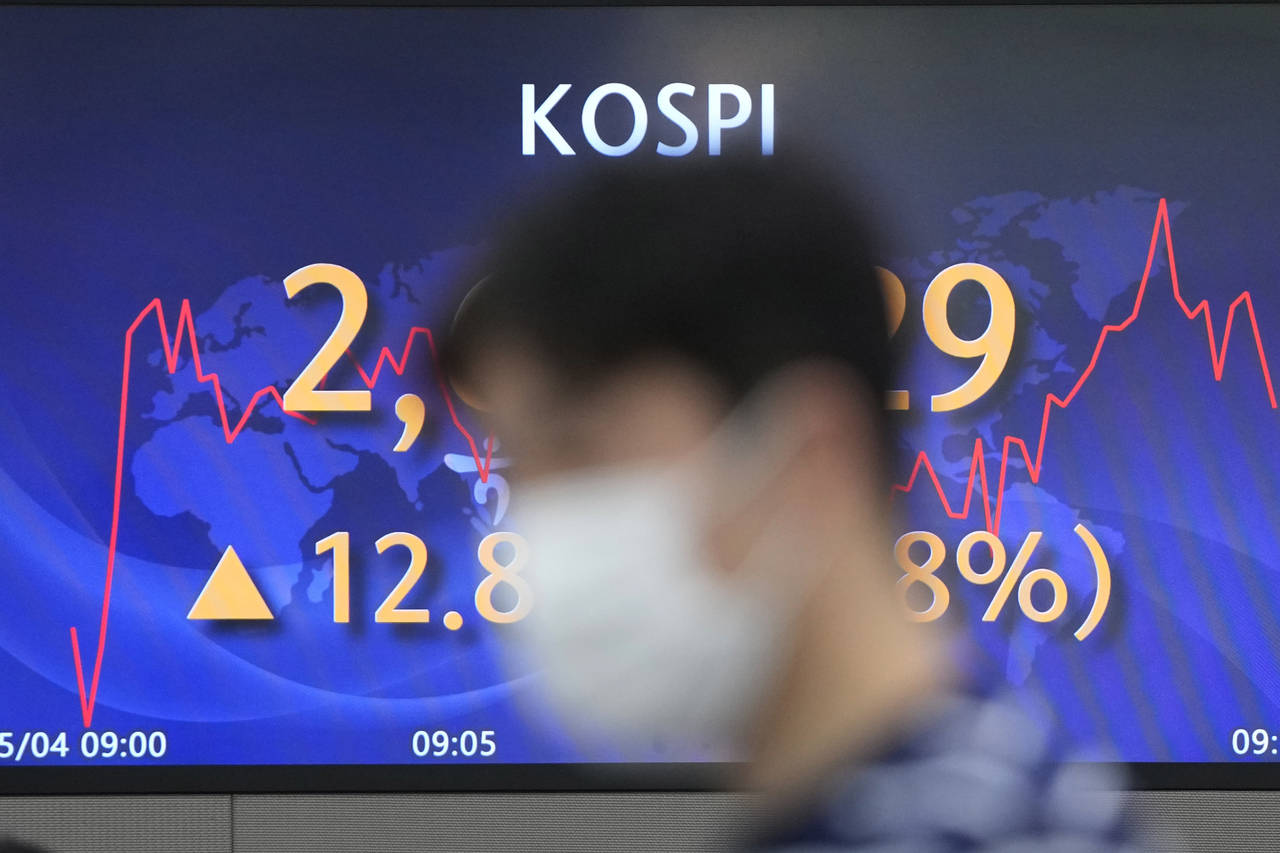A currency trader walks near the screen showing the Korea Composite Stock Price Index (KOSPI) at a ...