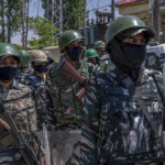 
              Paramilitary soldiers stand guard during a protest by Kashmiri Hindus, locally known as Pandits, against the killing of Rahul Bhat, also a Pandit, on the outskirts of Srinagar, Indian controlled Kashmir, Friday, May 13, 2022. Hindus in Indian-controlled Kashmir staged protests on Friday a day after assailants shot and killed the government employee from the minority community. It was the first time that Pandits, an estimated 200,000 of whom fled Kashmir after an anti-India rebellion erupted in 1989, simultaneously organized street protests at several places in the Muslim-majority region. (AP Photo/Dar Yasin)
            