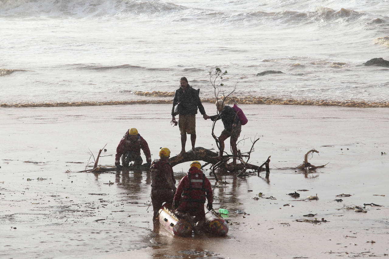 A couple, centre, attempt to make their way through muddy waters on a beach near Durban, South Afri...