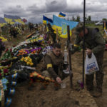 
              Two national guard visit the grave of a late soldier in Kharkiv cemetery, eastern Ukraine, Sunday, May 22, 2022. (AP Photo/Bernat Armangue)
            