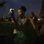 Models use their phone lights during a power outage to put on make-up before the start of the third Ouaga Fashion Week, Friday May 13, 2022 in Ouagadougou, Burkina Faso. Ouaga Fashion Week returned to the Burkinabe capital after a two year COVID-19 related break. (AP Photo/Sophie Garcia)