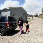 
              Martina Gonzales and her grandson, Lukas Lee Mora, 4, walk outside of their home in Las Vegas, N.M., as a plume of smoke rises in the distance Tuesday, May, 3, 2022. Flames raced across more of New Mexico's pine-covered mountainsides Tuesday, charring more than 217 square miles (562 square kilometers) over the last several weeks. Gonzales and her husband have packed up their valuables and are ready to leave the area if the fire tops the ridge behind their house. (AP Photo/Thomas Peipert)
            
