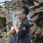 
              A woman stands next to a destroyed house in Mariupol, in territory under the government of the Donetsk People's Republic, eastern Ukraine, Tuesday, May 17, 2022. (AP Photo/Alexei Alexandrov)
            