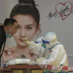 
              A medical worker in protective gear collects a sample from a worker at a COVID testing site setup outside a shopping mall on Sunday, May 22, 2022, in Beijing. (AP Photo/Andy Wong)
            