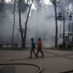 
              People walk at a local park as firefighters extinguish a fire following a Russian bombardment in Kharkiv, Ukraine, Tuesday, May 3, 2022. (AP Photo/Felipe Dana)
            
