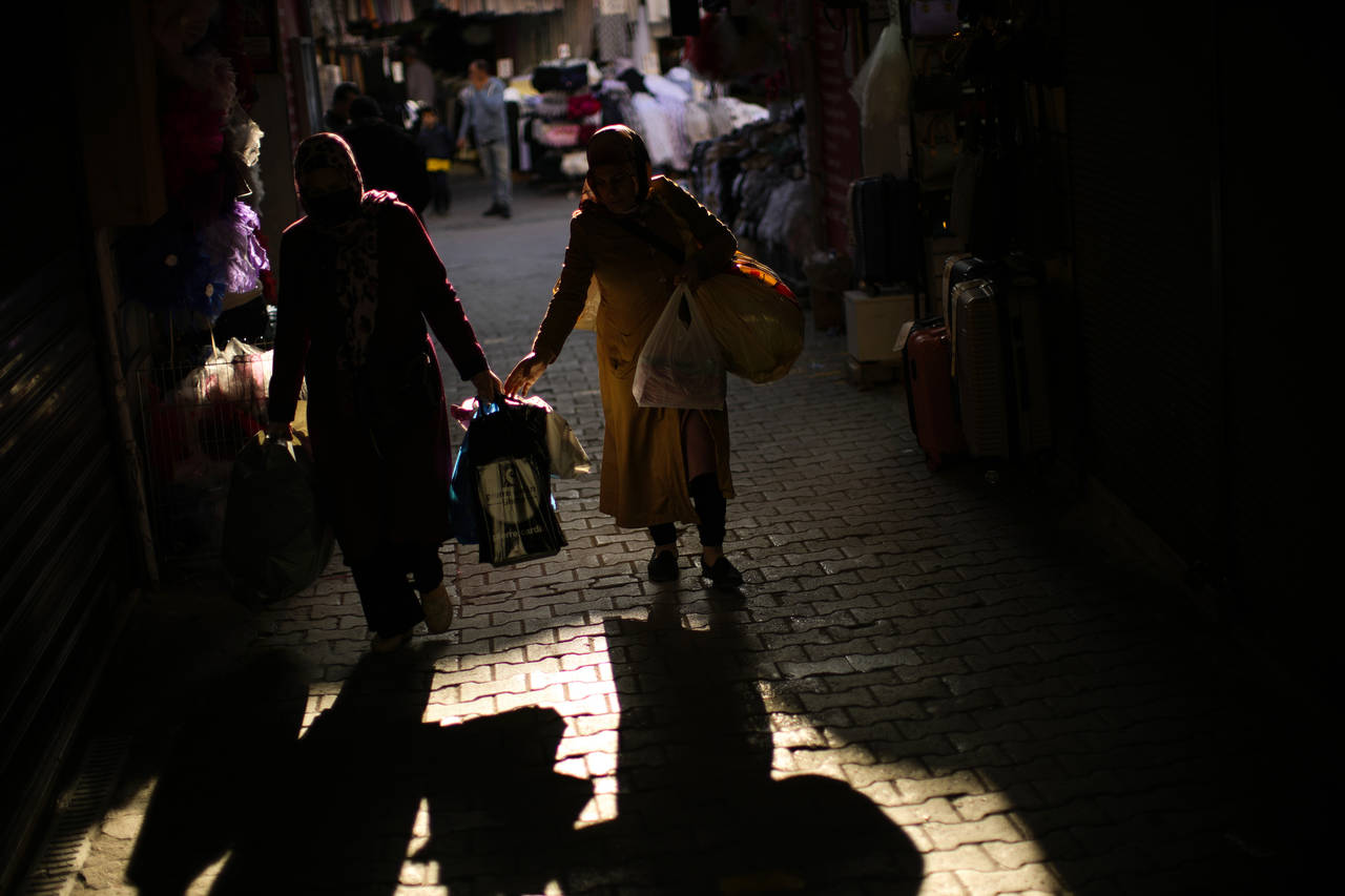 Women carry bags with goods in a commercial street in Istanbul, Turkey, Thursday, April 14, 2022. T...