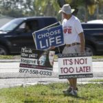 
              Dave Behrle, 70, of Safety Harbor picks up signs after standing outside the All Women's Health Center of Clearwater on Tuesday, May 3, 2022. A draft of a U.S. Supreme Court brief was leaked Monday that suggests the court could be poised to overturn the landmark 1973 Roe v. Wade case. (Chris Urso/Tampa Bay Times via AP)
            