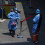 
              A worker in protective gear carries a bag of COVID test samples at a testing site on Sunday, May 22, 2022, in Beijing. (AP Photo/Andy Wong)
            