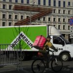 A food delivery courier rides a bicycle along a street passing a huge letter Z, which has become a symbol of the Russian military, on a building in a street in Moscow, Russia, Friday, May 6, 2022. The Russian holiday of Victory Day brings out patriotic displays of flags, military parades and marches by veterans groups celebrating the country's triumph over Nazi Germany in 1945. At first glance, the preparations for Monday's celebration seem to be the same as ever. But the mood this year is very different, because Russian troops are fighting and dying in neighboring Ukraine.  (AP Photo/Alexander Zemlianichenko)