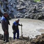 
              Workers stand next to a crater after night shelling in Kramatorsk, Ukraine, Thursday, May 5, 2022. (AP Photo/Andriy Andriyenko)
            