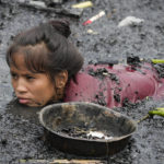 
              A woman searches for nails and other metal scraps from remains of burned houses that were gutted during a fire at a poor bayside village in the district of Tondo, Manila, Philippines on Friday, May 20, 2022. Investigators said about 300 families became homeless after the fire that happened Thursday night. (AP Photo/Aaron Favila)
            