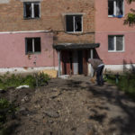 
              Resident Alexander, 67, sweeps the entrance of his building damaged by shelling in Kutuzivka, near Kharkiv, eastern Ukraine, Friday, May 27, 2022. (AP Photo/Bernat Armangue)
            