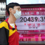 
              A man wearing a face mask walks past a bank's electronic board showing the Hong Kong share index in Hong Kong, Wednesday, May 18, 2022. Asian stock markets were mixed Wednesday after Wall Street rose and the Federal Reserve chairman said it will raise interest rates further if needed to cool inflation.(AP Photo/Kin Cheung)
            