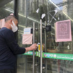 
              A man tries to receive medicine he bought at a pharmacy through its closed glass doors in Shanghai, China, Sunday, May 22, 2022. Numerous residential compounds in Beijing have restricted movement in and out, although conditions remain far less severe than in Shanghai, where millions of citizens have been under varying degrees of lockdown for two months. (AP Photo/Chen Si)
            