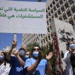 
              A nurse holds an Arabic placard that reads: "Monetary policy that stifles hospitals is a failure," as he protests with other medical workers and doctors the deteriorating economic conditions, outside the Central Bank, in Beirut, Lebanon, Thursday, May 26, 2022. The syndicates of doctors in Beirut and the North as well as the Syndicate of Private Hospital Owners declared a two-day general strike Thursday and Friday. (AP Photo/Hussein Malla)
            