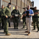 
              Homeland Security Secretary Alejandro Mayorkas, second from right, looks up along with U.S Border Patrol agents as a drone flies overhead as he tours a section of the border wall Tuesday, May 17, 2022, in Hidalgo, Texas. (Joel Martinez/The Monitor via AP, Pool)
            