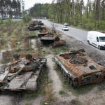 
              Cars pass by destroyed Russian tanks in a recent battle against Ukrainians in the village of Dmytrivka, close to Kyiv, Ukraine, Monday, May 23, 2022. (AP Photo/Efrem Lukatsky)
            