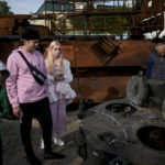 
              People look at a destroyed Russian tanks placed as a symbol of war at Mykhailivs'ka Square downtown Kyiv, Ukraine, Monday, May 23, 2022. (AP Photo/Natacha Pisarenko)
            
