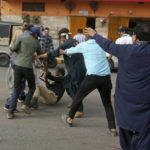 
              Supporters of Pakistan's key opposition party scuffle with a police officer knocked to the ground during an anti-government rally, in Karachi, Pakistan, Wednesday, May 25, 2022. Pakistani police have fired tear gas and scuffled with stone-throwing supporters of defiant former Prime Minister Imran Khan as they gathered for planned marches Wednesday toward central Islamabad for a rally he hopes will bring down the government and force early elections. (AP Photo/Fareed Khan)
            