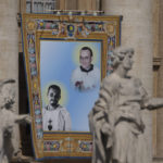 
              The tapestry depicting Giustino Maria Russolillo (1891-1955), top, and Charles de Foucauld (1858-1916), hangs in St. Peter's Square at The Vatican, Sunday, May 15, 2022, during their canonization mass celebrated by Pope Francis. Francis created ten new saints on Sunday, rallying from knee pain that has forced him to use a wheelchair to preside over the first canonization ceremony at the Vatican in over two years. (AP Photo/Gregorio Borgia)
            
