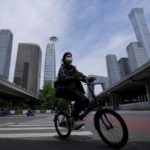 
              A woman wearing a face mask rides across a quiet intersection in the central business district as most nonessential workers in the district have been ordered to work from home in the Chaoyang district on Wednesday, May 11, 2022, in Beijing. Shanghai reaffirmed China's strict "zero-COVID" approach to pandemic control Wednesday, a day after the head of the World Health Organization said that was not sustainable and urged China to change strategies. (AP Photo/Andy Wong)
            