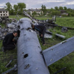 
              Oleksiy Polyakov, right, and Roman Voitko check the remains of a destroyed Russian helicopter lie in a field in the village of Malaya Rohan, Kharkiv region, Ukraine, Monday, May 16, 2022. (AP Photo/Bernat Armangue)
            