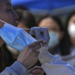 
              A woman holds her mask as she gets swabbed during public COVID-19 testing in the Chaoyang district on Wednesday, May 11, 2022, in Beijing. Shanghai reaffirmed China's strict "zero-COVID" approach to pandemic control Wednesday, a day after the head of the World Health Organization said that was not sustainable and urged China to change strategies. (AP Photo/Andy Wong)
            