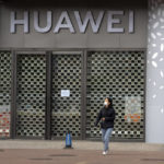 
              A woman wearing a face mask walks past a Huawei store temporarily closed due to coronavirus-related restrictions in Beijing, Thursday, May 12, 2022. China's leaders are struggling to reverse a deepening economic slump while keeping a "zero-COVID" strategy that has shut down Shanghai and other cities. (AP Photo/Mark Schiefelbein)
            
