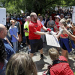 
              A counter protester, center, is shouted down and has his megaphone taken away by rally attendees for pro-gun control efforts at Discovery Green Park, across the street from the National Rifle Association Annual Meeting held at the George R. Brown Convention Center Friday, May 27, 2022, in Houston. (AP Photo/Michael Wyke)
            