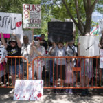 
              Protesters hold up their signs condemning the National Rifle Association's annual meeting outside the George R. Brown Convention Center in Houston, Friday, May 27, 2022. (AP Photo/Jae C. Hong)
            