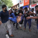 
              An injured student is carried by colleagues as police fire tear gas and water cannons to disperse protesting members of the Inter University Students Federation during an anti government protest in Colombo, Sri Lanka, Thursday, May 19, 2022. Sri Lankans have been protesting for more than a month demanding the resignation of President Gotabaya Rajapaksa, holding him responsible for the country's worst economic crisis in recent memory. (AP Photo/Eranga Jayawardena)
            
