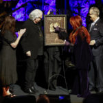Wynonna Judd, second from the right, touches the plaque as sister Ashley Judd, left, Ricky Skaggs, and MC Kyle Young CEO of the Country Music Hall of Fame & Museum look on during the Medallion Ceremony at the Country Music Hall of Fame on Sunday, May 1, 2022, in Nashville, Tenn. (Photo by Wade Payne/Invision/AP)