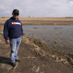
              Don Schneider stands in front of an augmentation pond on his property Friday, April 29, 2022, in Ovid, Colo. He pumps water from a shallow aquifer for irrigation, and uses supply from the South Platte River to replenish the wells. (AP Photo/Brittany Peterson)
            