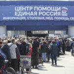 
              Local civilians line up to get humanitarian aid distributed in the United Humanitarian Center in Mariupol, in territory under the government of the Donetsk People's Republic, eastern Ukraine, Monday, May 2, 2022, with a poster reading 'Help center. United Russia'. (AP Photo/Alexei Alexandrov)
            